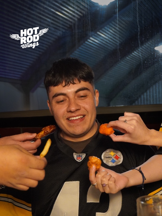 Cliente con jersey de Steelers comiendo alitas Hot Rod Wings