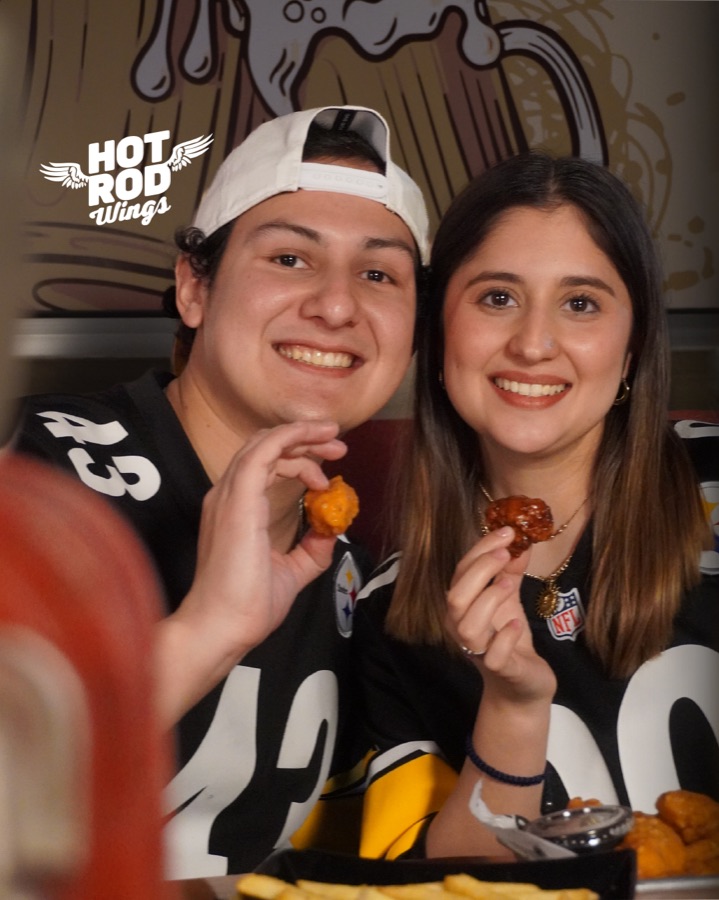 Pareja con jersey de Steelers disfrutando alitas en Hot Rod Wings